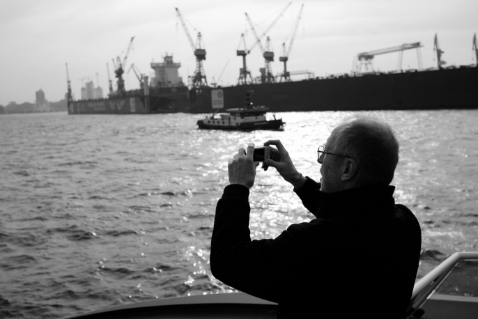 A man takes photos of ships in a harbor